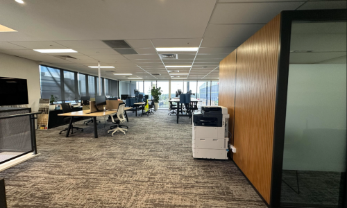 Clean and professionally organized government office workspace with rows of desks, gray patterned carpet, and modern facilities managed by CJM Cleaning & Facilities Services.